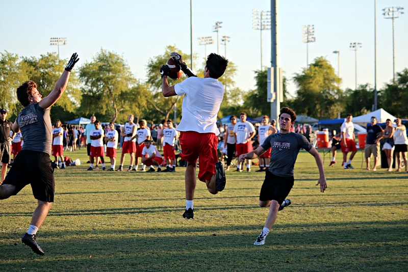 Three football players prepare to throw and catch a football